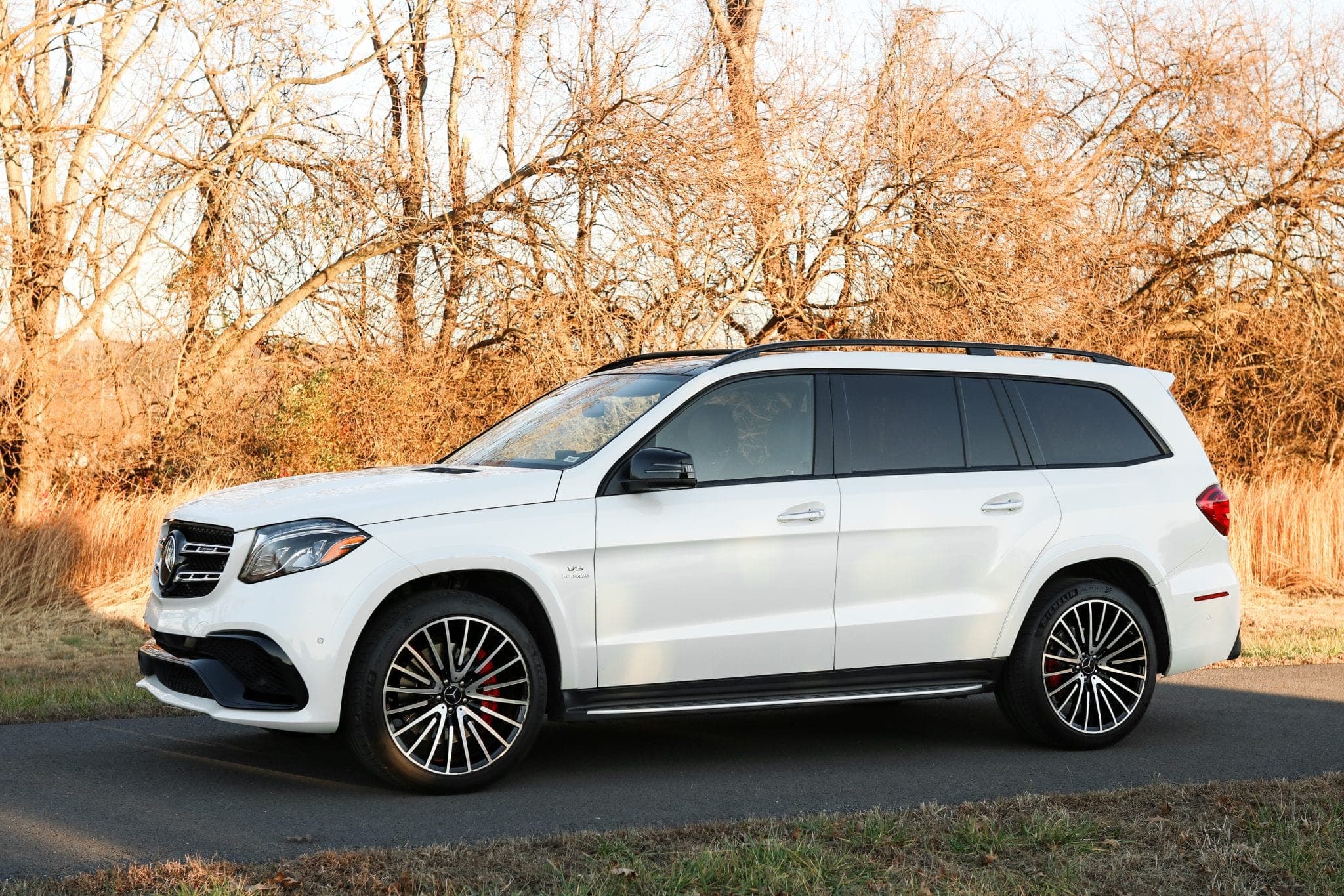 White Mercedes-AMG GLS 63 photographed from the front three-quarter on a road in low golden light