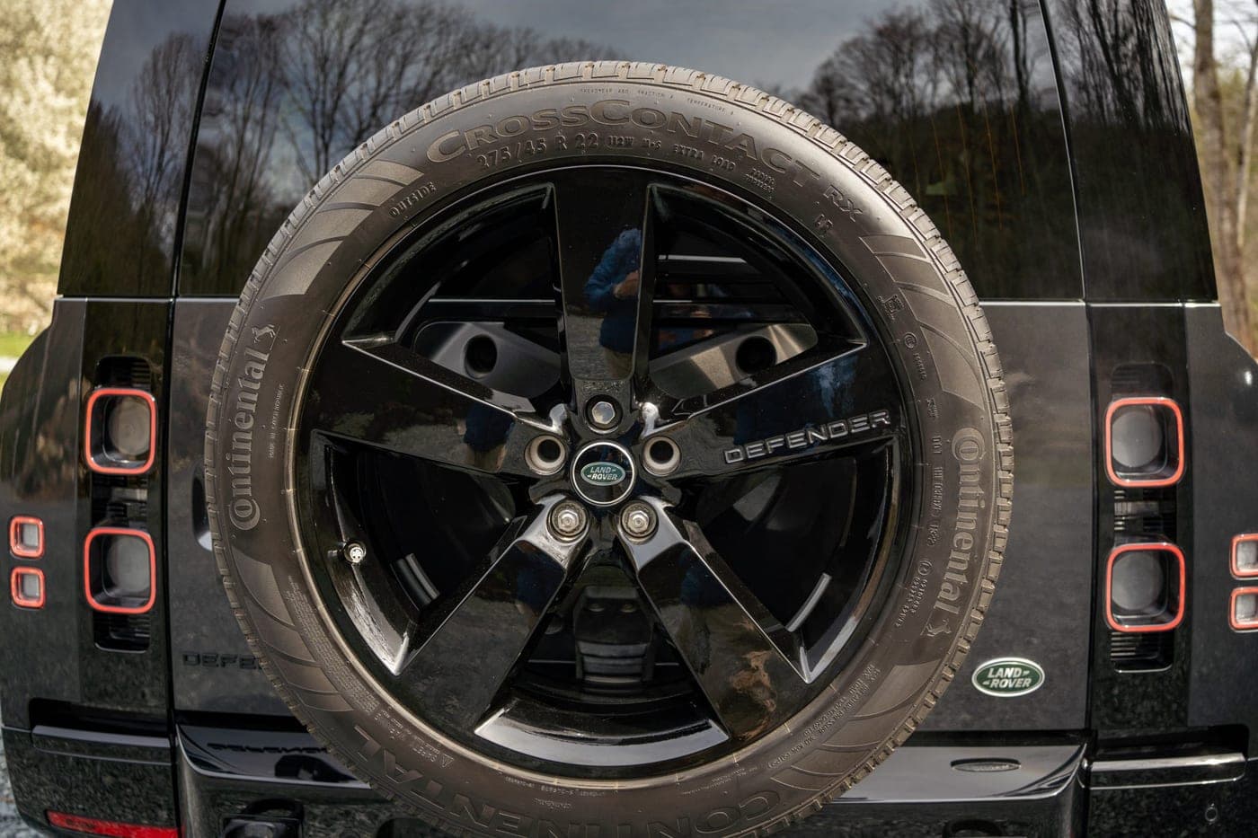 Tailgate-mounted spare wheel and rear light clusters of a Land Rover Defender 90, photographed straight on