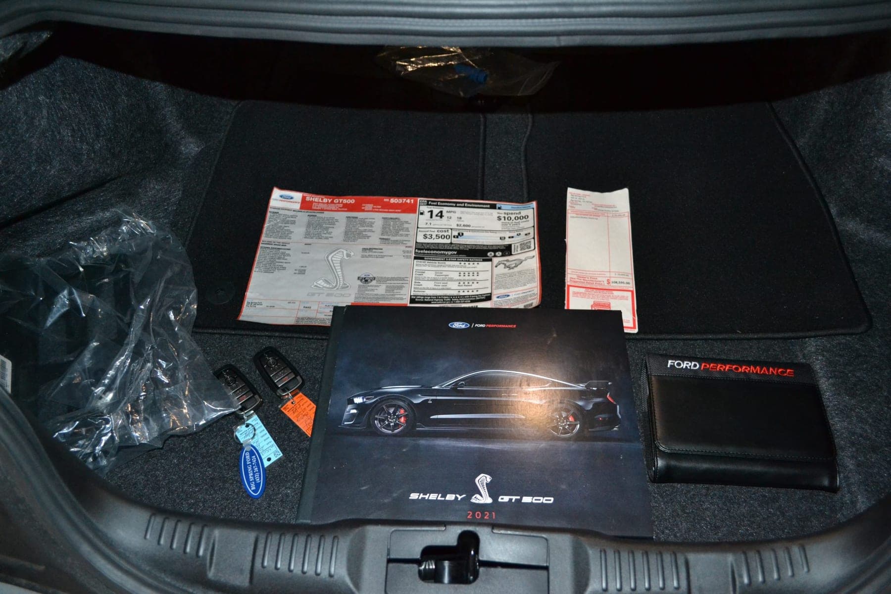 Window sticker, manuals, keys and a Ford Performance document wallet laid out in the boot of a Shelby GT500, in a Carviondealer listing photograph