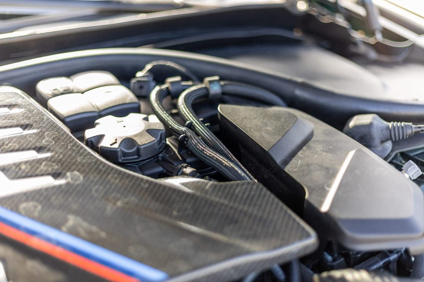 Carbon-fibre engine cover and braided lines under the bonnet of a BMW M5 CS