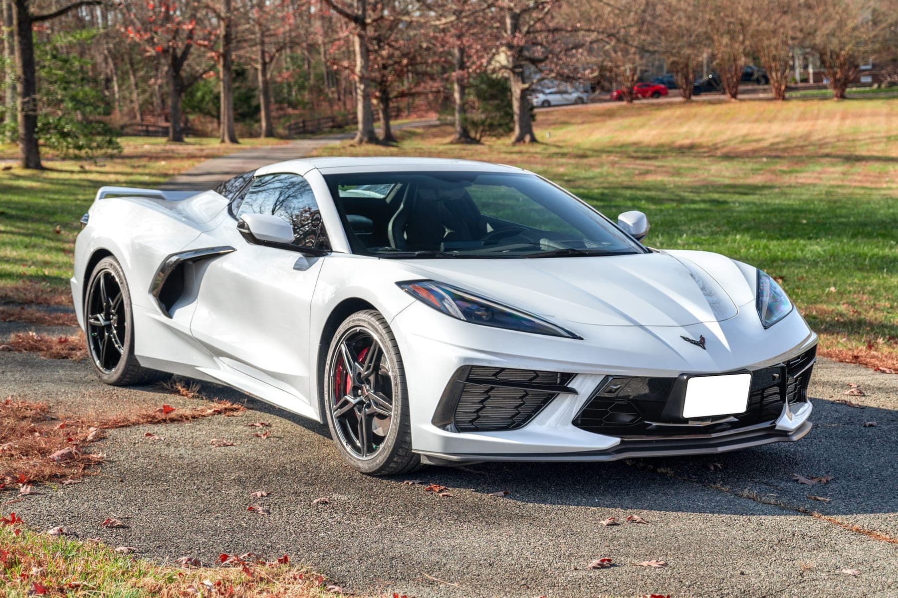 White Corvette Stingray convertible photographed from the front three-quarter on a gravel drive — the kind of frame that opens a listing