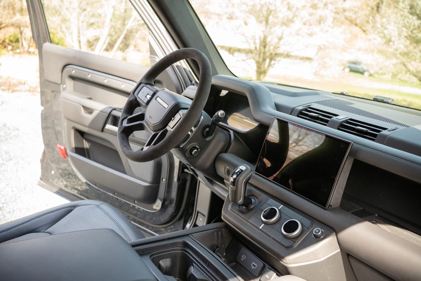 Dashboard, steering wheel and exposed structural crossbeam of a Land Rover Defender 90, photographed through the open driver's door