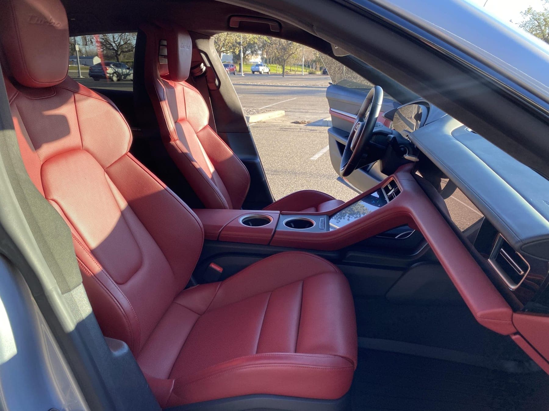 Red leather front seats and centre console of a Porsche Taycan Turbo Cross Turismo, seen through the open driver's door