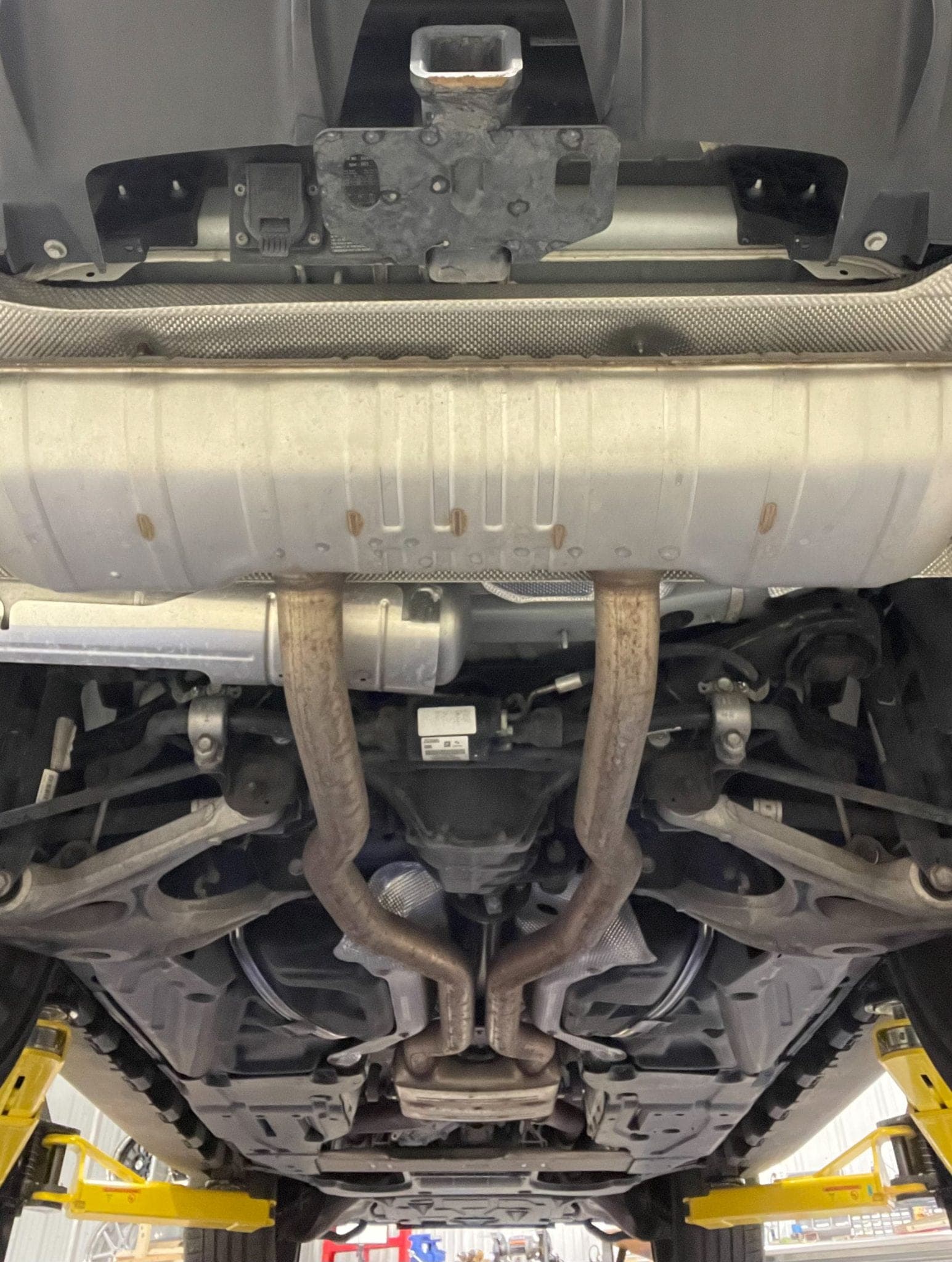 Rear underbody of a Mercedes-AMG GLS 63 on a lift, showing the silencer, exhaust routing, rear differential and suspension arms